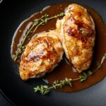 Tender Chicken With Thick Gravy, Isolated On A Matte Black Plate With Artistic Streaks Of Gravy And A Fresh Thyme Sprig