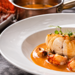 Filet de poisson nappé de bisque de homard, accompagné de morceaux de crustacés