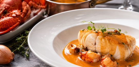 Filet de poisson nappé de bisque de homard, accompagné de morceaux de crustacés